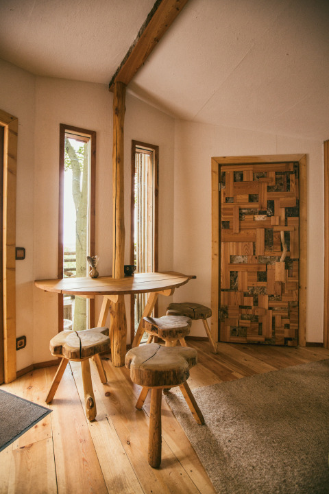Gemütlicher Innenraum aus Holz in der Baumhausherberge Robins Nest Glamping, rustikale Möbel und Fenster.