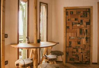Interno rustico in legno del glamping Baumhausherberge Robins Nest con mobili naturali e finestre.