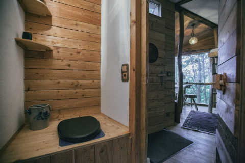 Træhytte med rustik indretning, træpaneler, bænk og udsigt til natur gennem vinduer, glamping i Hessen.