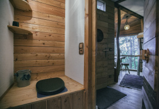 Intérieur rustique de cabane dans les arbres à Hessen, banc en bois et vue nature, hébergement glamping.