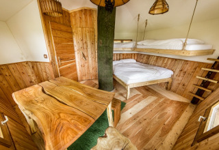 Habitación glamping de madera con literas y mesa rústica en Baumhausherberge Robins Nest, Boomhutten Hessen.