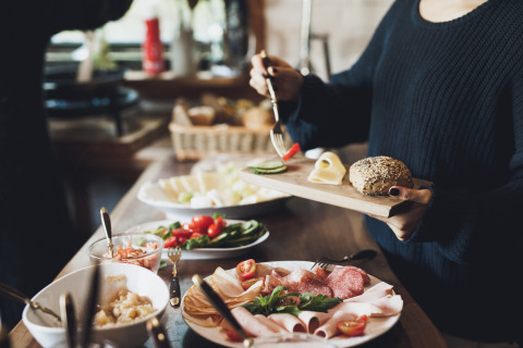 Frühstück mit frischem Brot, Aufschnitt, Käse und Gemüse bei Baumhausherberge Robins Nest Glamping.