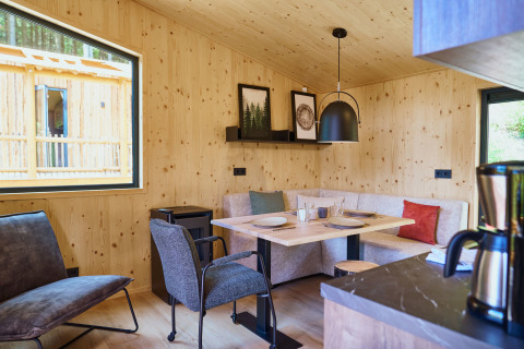 Moderne houten hut met sfeervolle eethoek en grote ramen bij UplandParcs Sauerland, Noordrijn-Westfalen.
