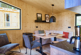 Moderne houten hut met sfeervolle eethoek en grote ramen bij UplandParcs Sauerland, Noordrijn-Westfalen.