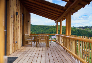 Boomhut met overdekt terras en uitzicht op groene heuvels bij UplandParcs Sauerland Boomhutten.