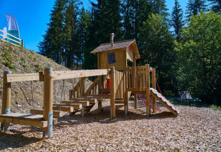 Parco giochi con casetta in legno e ponte sospeso a UplandParcs Sauerland - Boomhutten glamping in Renania Settentrionale-Vestfalia.