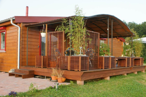 Bungaló de madera con terraza cubierta y plantas en Camping & Vakantiepark Orsingen, Baden-Württemberg.