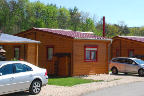 Bungalow in legno al Camping & Vakantiepark Orsingen - Bungalow Baden-Württemberg con auto e alberi dietro.