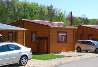 Houten bungalow bij Camping & Vakantiepark Orsingen - Bungalow Baden-Württemberg met auto's en bomen achteraan.