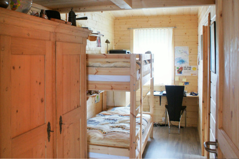 Chambre en bois avec lits superposés, bureau et armoire au Camping & Vakantiepark Orsingen.