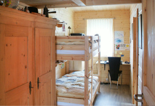 Billede af et hyggeligt træværelse med køjeseng, skrivebord og skab i Camping & Vakantiepark Orsingen.