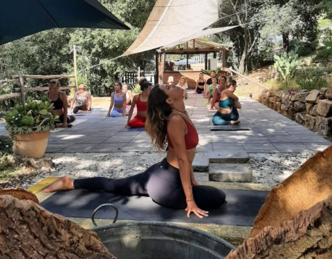 Outdoor yoga class at Agriturismo & Glamping Serraiola Alta in Tuscany, Italy, with participants posing.