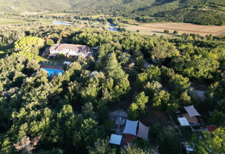 Aerial view of Agriturismo & Glamping Serraiola Alta in Tuscany with glamping tents, forest, and pool.