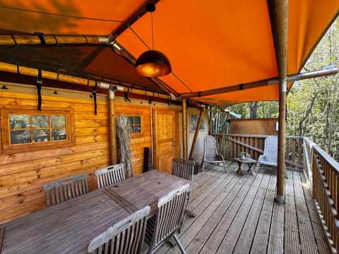 Holzterrasse mit Sitzbereich und orangefarbener Überdachung bei Agriturismo & Glamping Serraiola Alta in der Toskana.