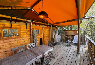 Terraza de madera con muebles y toldo naranja en Agriturismo & Glamping Serraiola Alta, Toscana.