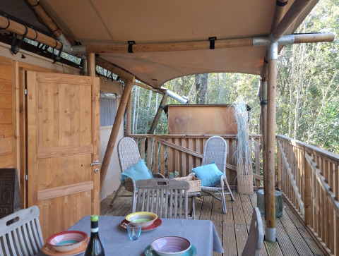 Wooden terrace with set dining table and chairs at Agriturismo & Glamping Serraiola Alta in Tuscany, Italy.