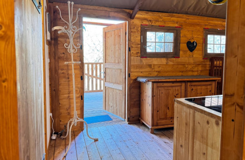 Interior de madera de alojamiento glamping en Agriturismo & Glamping Serraiola Alta con puerta abierta.