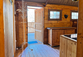 Interior de madera de alojamiento glamping en Agriturismo & Glamping Serraiola Alta con puerta abierta.