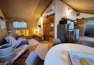 Vista interna di una tenda glamping di lusso presso Agriturismo & Glamping Serraiola Alta con cucina e soggiorno.