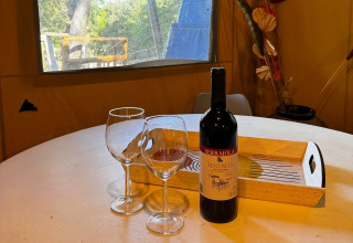 Ein Tisch im Glampingzelt mit zwei Weingläsern und einer Flasche Serraiola Lentisco im Glamping Serraiola Alta.