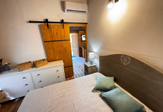 Gemütliches Glamping-Zimmer bei Agriturismo & Glamping Serraiola Alta mit Bett, Kommode und Holztür.