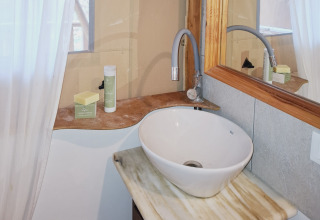 Moderne glampingbadkamer met wastafel, spiegel en toiletartikelen bij Agriturismo & Glamping Serraiola Alta.