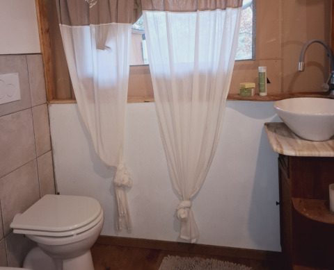 Badkamer met wc, waskom en gordijnen bij Agriturismo & Glamping Serraiola Alta in Toscane.