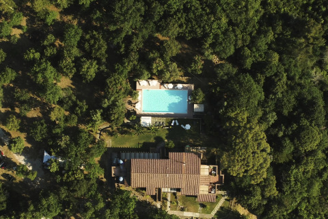 Luchtfoto van Agriturismo & Glamping Serraiola Alta in Toscane met zwembad en glampingtenten in het bos.