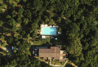 Luchtfoto van Agriturismo & Glamping Serraiola Alta in Toscane met zwembad en glampingtenten in het bos.