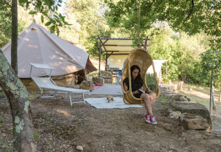 Vrouw ontspant in hangstoel voor glampingtent bij Agriturismo & Glamping Serraiola Alta in Toscane.