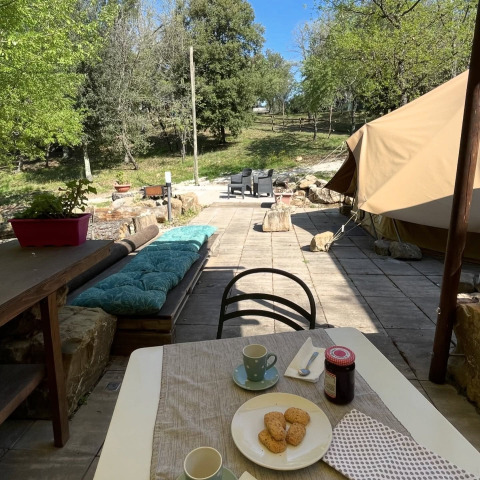 Glamping accommodation with tent, outdoor seating, and cookies on a table at Serraiola Alta in Tuscany.