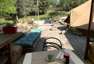 Glampingindkvartering med telt, udendørs siddepladser og snacks på et bord hos Serraiola Alta i Toscana.