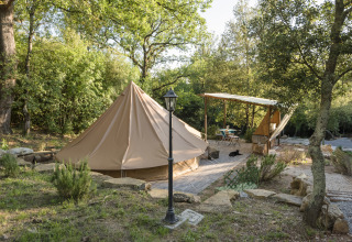 Glamping accommodation with a large canvas tent and shaded terrace surrounded by nature in Serraiola Alta, Tuscany.
