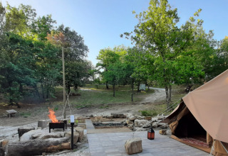 Glamping i Toscana med luksustelt og bålplads omgivet af grøn natur på Agriturismo & Glamping Serraiola Alta.