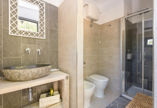 Moderne badeværelse i Agriturismo & Glamping Serraiola Alta med sten vask, bruser og bidet i Toscana.