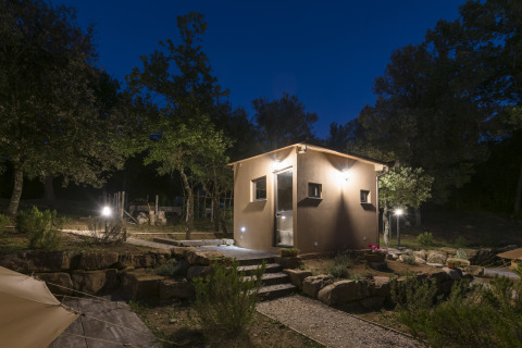 Oplyst glampinghytte ved Agriturismo & Glamping Serraiola Alta i Toscana om aftenen, omgivet af natur.