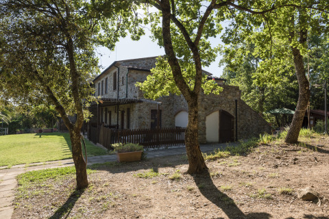 Stone house surrounded by trees at Agriturismo & Glamping Serraiola Alta, glamping tents in Tuscany, Italy.