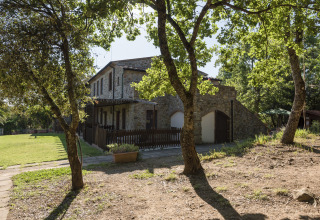 Casa in pietra circondata da alberi all'Agriturismo & Glamping Serraiola Alta, tende glamping in Toscana.