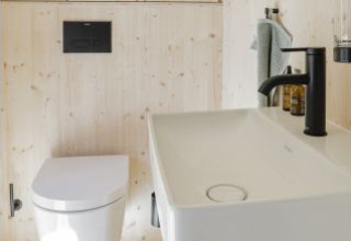 Bagno moderno nella sistemazione glamping Ostsee Baumhaus aan de Oostzee con WC e lavandino bianco.