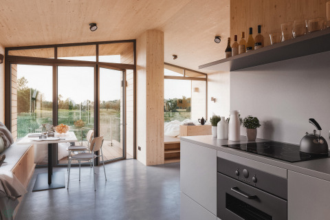 Moderne glampingaccommodatie Ostsee Baumhaus met grote ramen, licht houten interieur en strakke keuken.