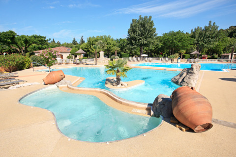 Outdoor swimming pool with large terracotta pots and palm trees at Camping Nature Parc l'Ardéchois Glamping Ardèche.