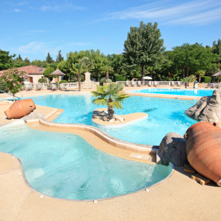 Outdoor swimming pool with large terracotta pots and palm trees at Camping Nature Parc l'Ardéchois Glamping Ardèche.