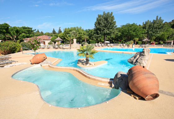 Piscina all'aperto con grandi vasi in terracotta e palme a Camping Nature Parc l'Ardéchois Glamping Ardèche.