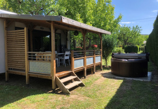 Glamping-Unterkunft bei Camping Nature Parc l'Ardéchois mit überdachter Terrasse und Whirlpool im Grünen.