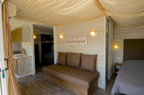 Interior de alojamiento glamping en Camping Nature Parc l'Ardéchois con cama cómoda y cocina moderna.