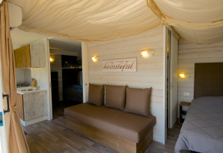Interior de alojamiento glamping en Camping Nature Parc l'Ardéchois con cama cómoda y cocina moderna.