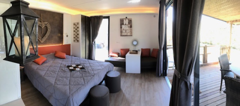 Glamping accommodation with stylish bedroom, cozy decor, and private terrace at Ardèche Nature Parc site.