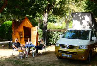 Glamping au Camping Nature Parc l'Ardéchois avec cabane en bois, van VW et vacanciers profitant du site.