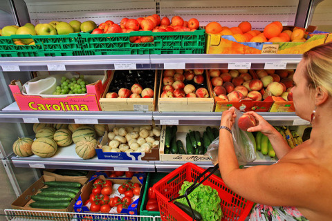 Woman selects peaches at the store in Camping Nature Parc l'Ardéchois - Glamping Ardèche during glamping stay.
