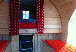Vista interior de glamping en Stuttgart Cannstatter Wasen con cojines rojos y cortinas de lunares.